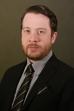 a man wearing a black suitcoat with a black and gold tie and pocket square