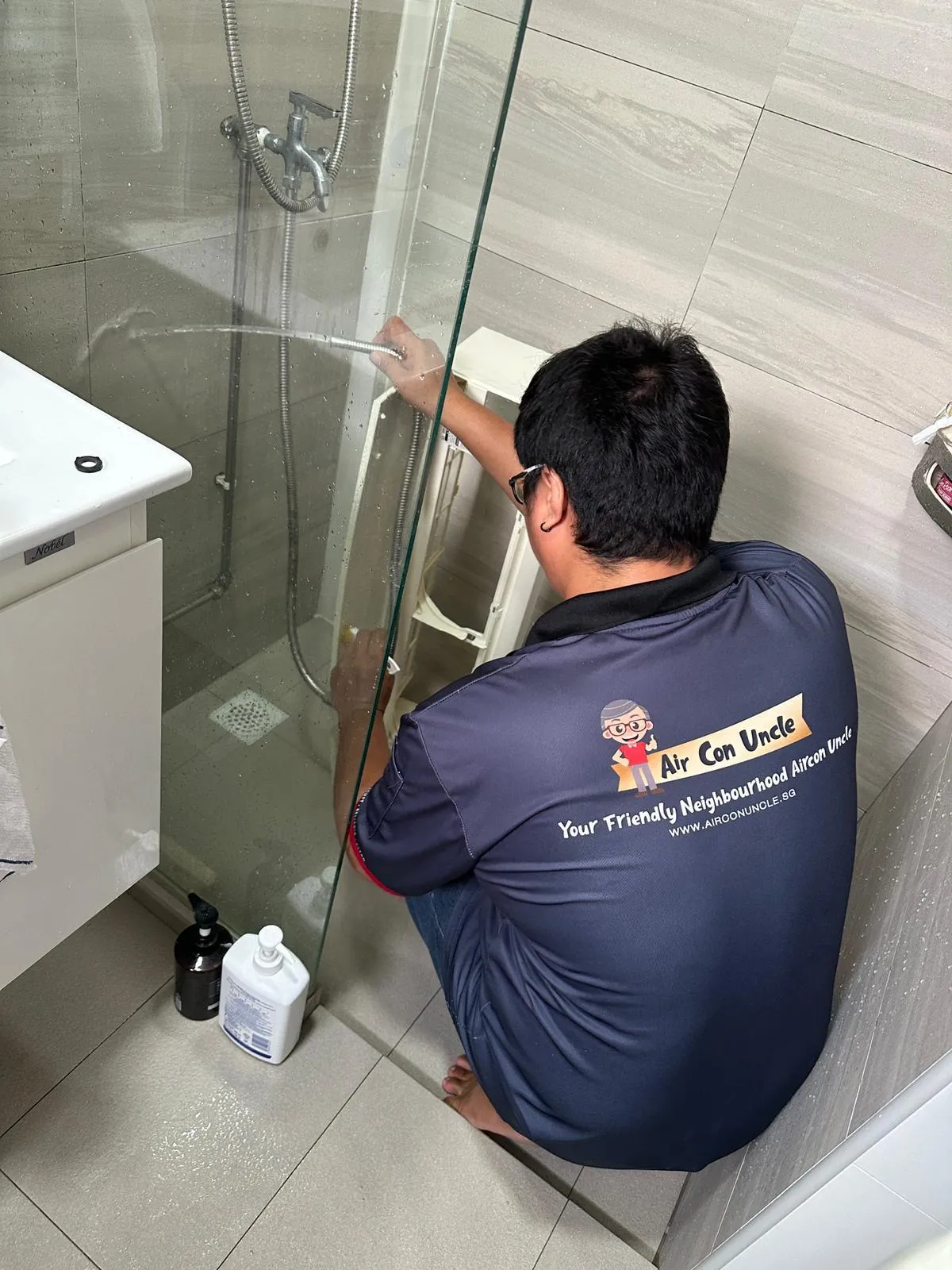 Technician performing aircon chemical overhaul on a wall-mounted unit using , standing on a ladder to clean the interior components for optimal airflow.