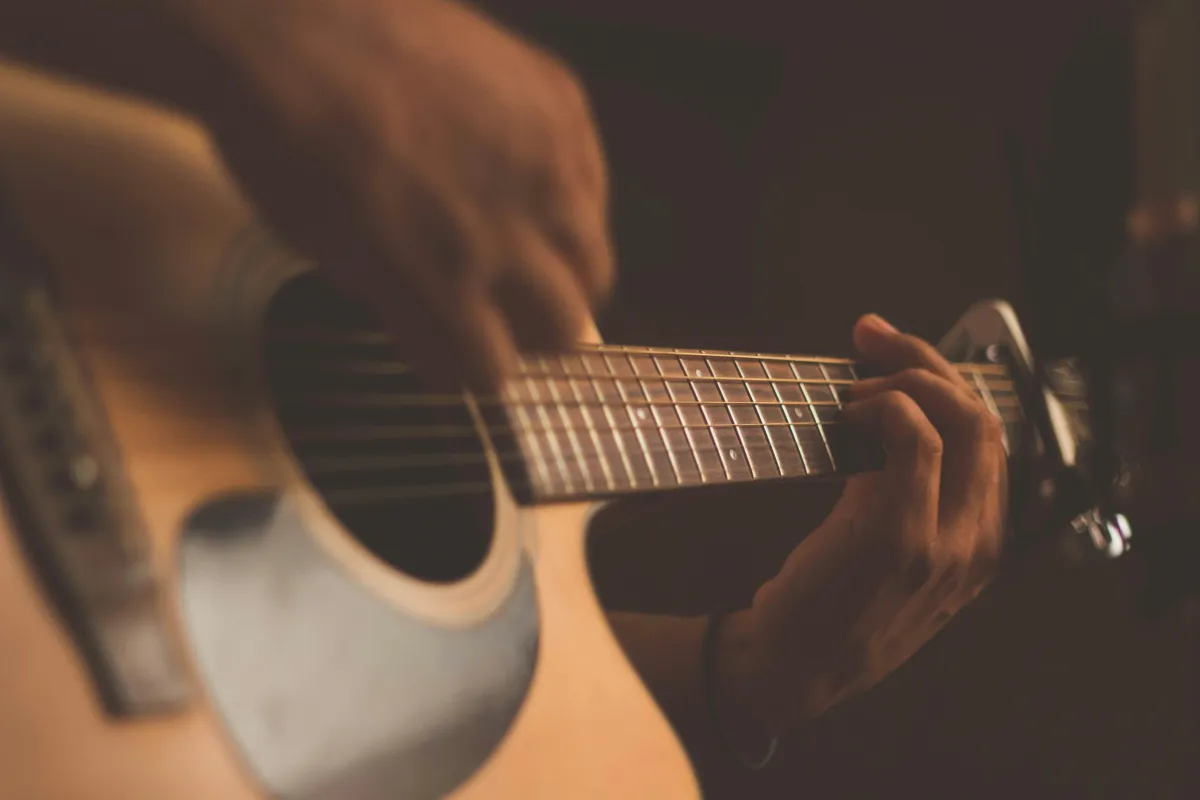 Man playing acoustic guitar by a campfire with friends