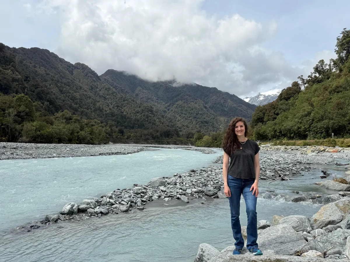 Sara Lorraine standing near glacier melt in New Zealand