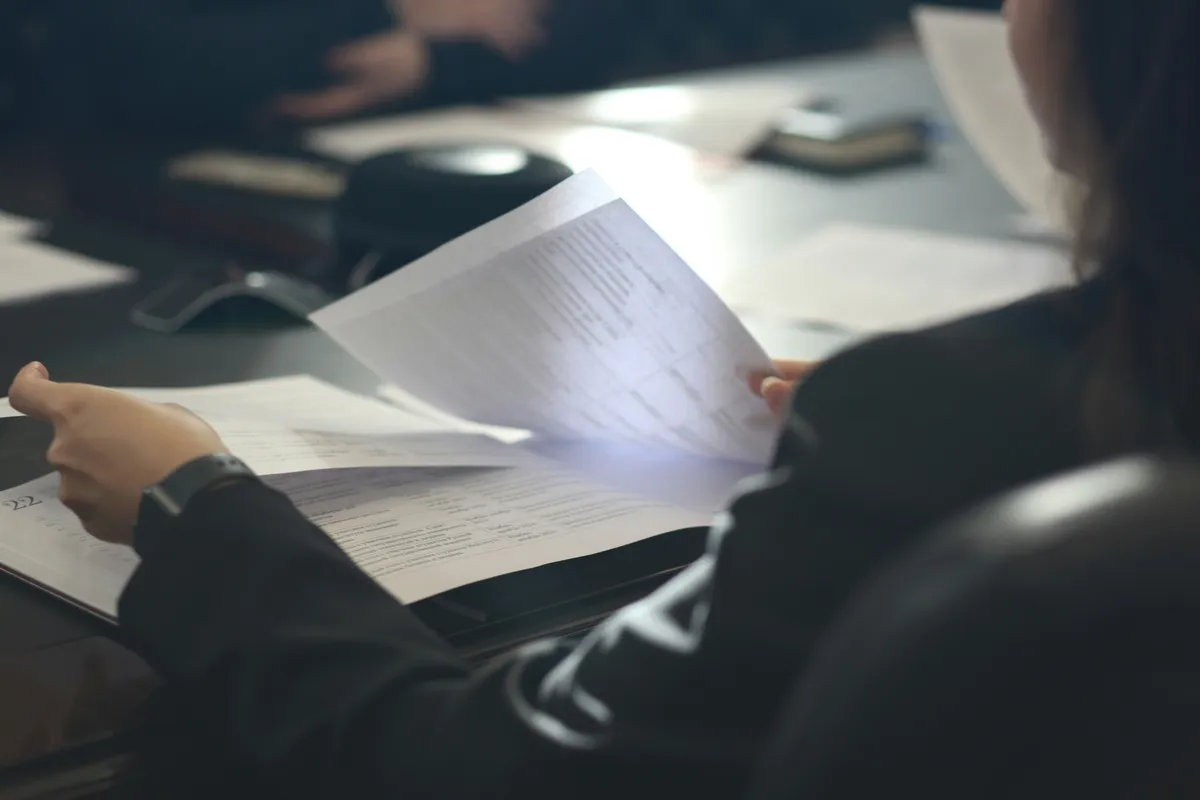 Close-up of a person reviewing paper documents at a desk