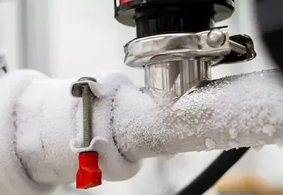 Ice-covered water pipes and frozen valve in need of emergency thaw and repair service