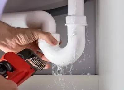 Leaking drain pipe under bathroom sink being repaired with pipe wrench by Pickerington Emergency Plumbers