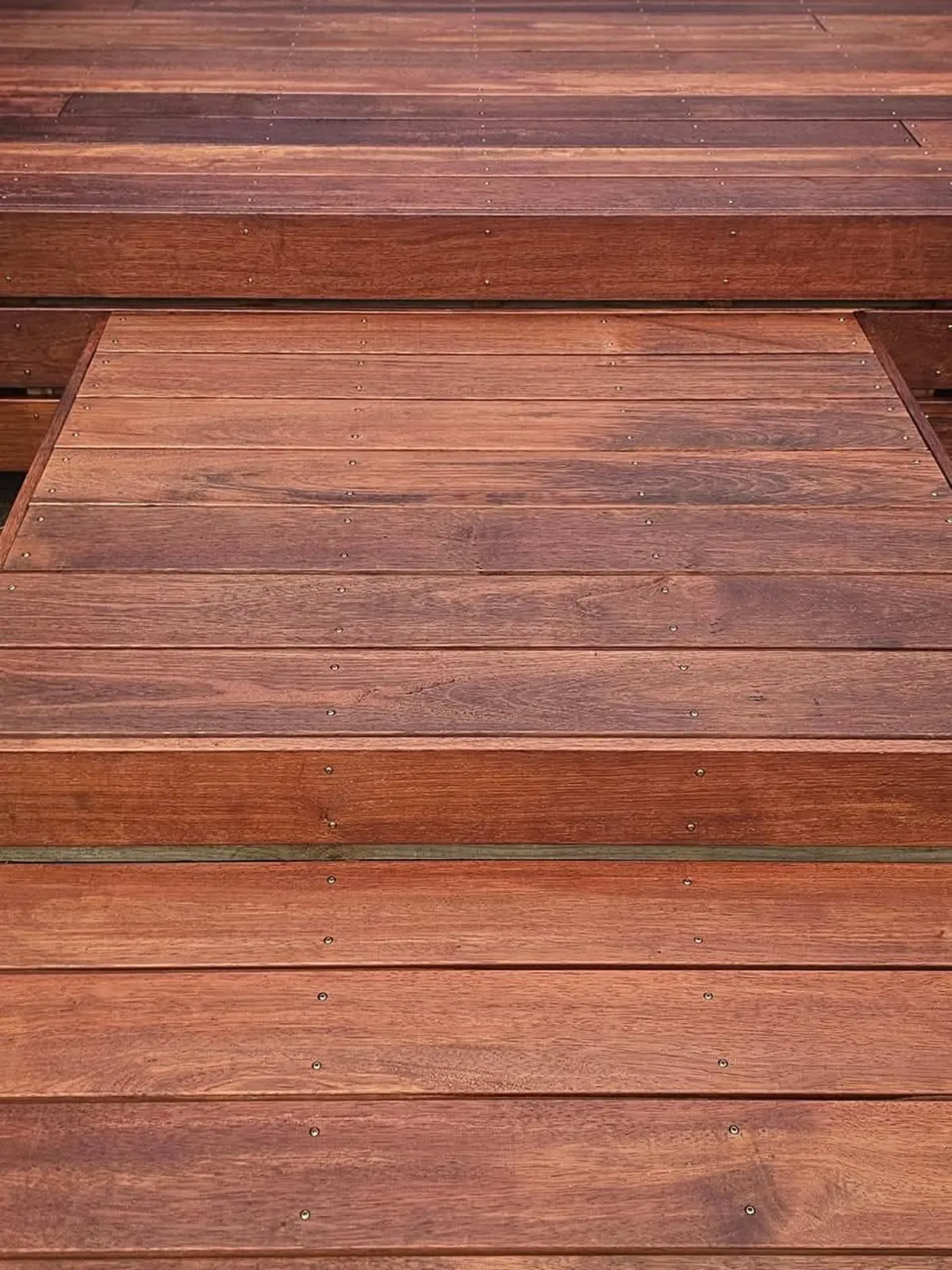 Freshly cleaned and coated timber deck with rich red-brown finish, ready for outdoor use