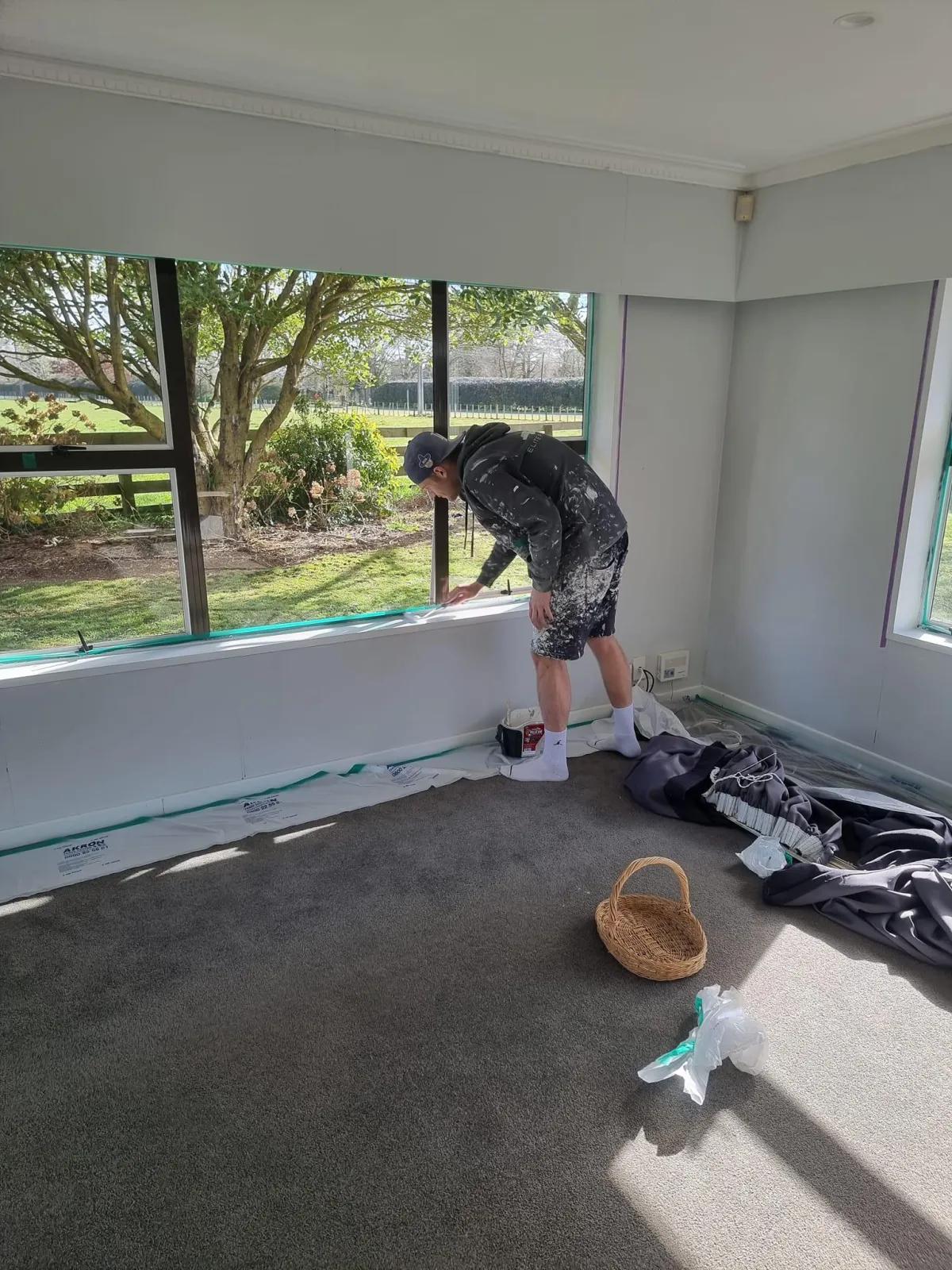 Elite Paint Co. painter preparing interior walls for painting in a sunlit Hamilton home