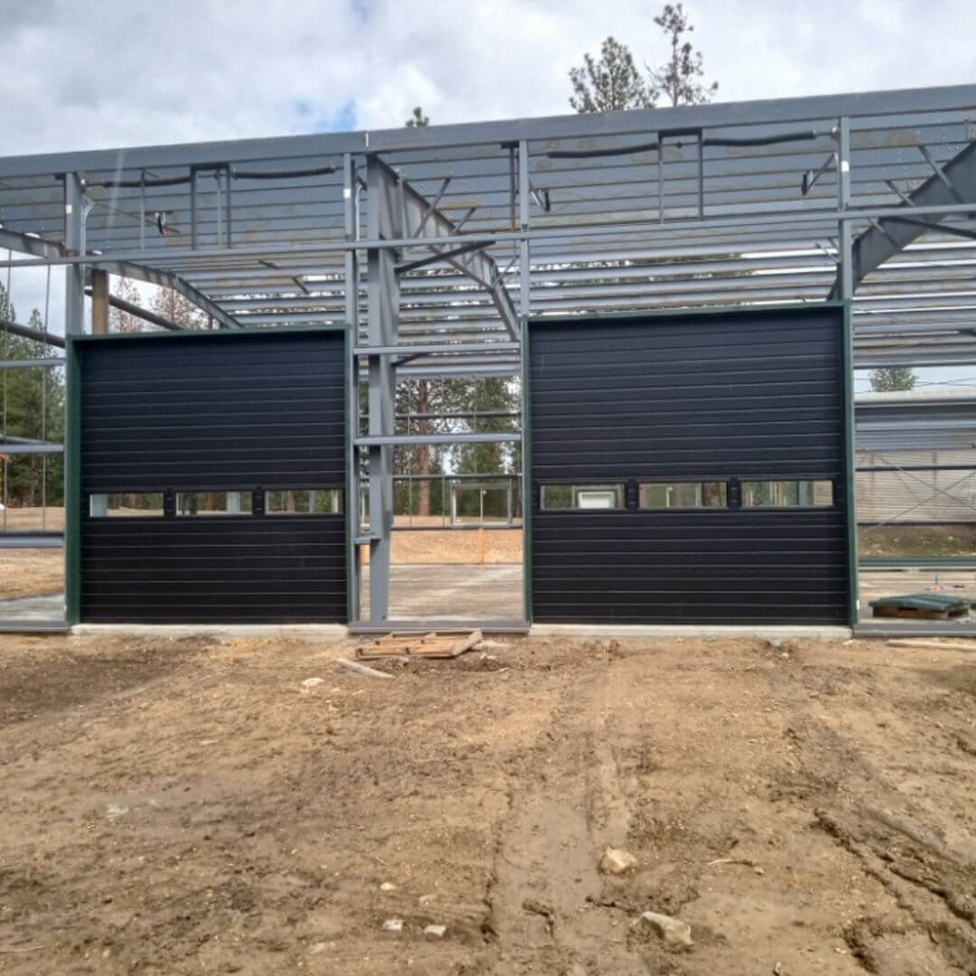 dark painted commercial garage doors being installed at a worksite in Kalispell, MT