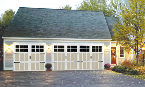 carriage-style new garage doors on a light tan siding house in Montana
