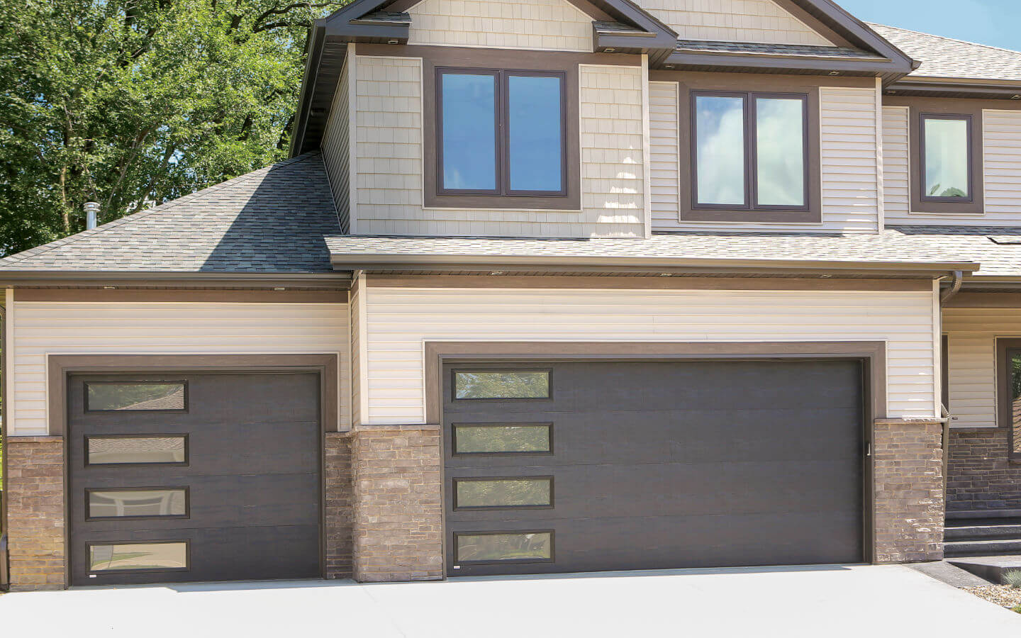 light brown house with modern windowed dark brown garage doors from Overhead Door™