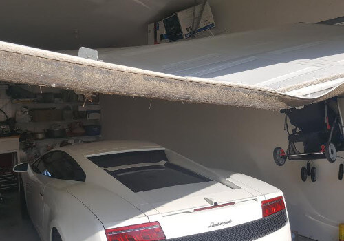 lamborghini in a garage with a dented broken garage door