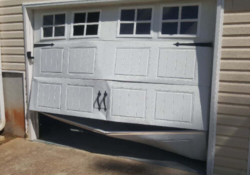 bent and busted garage door on a house