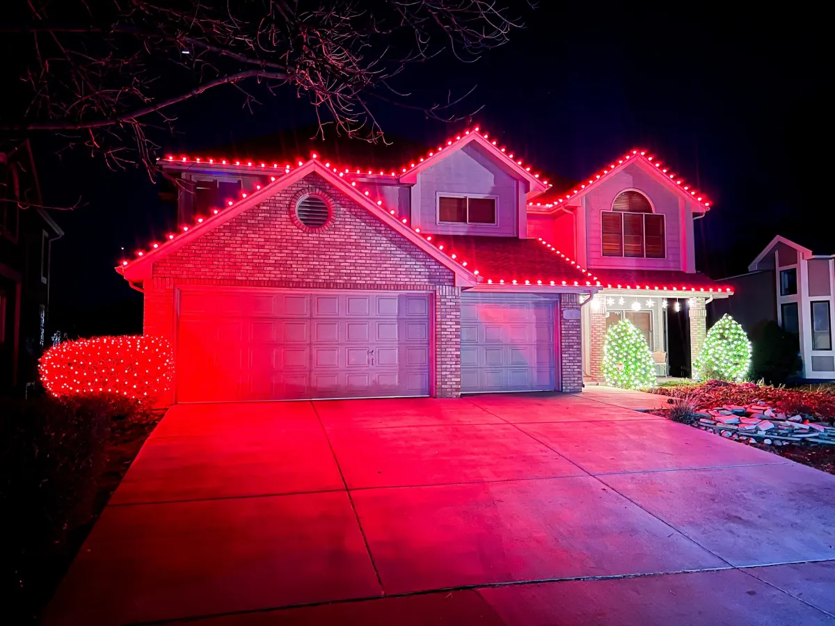 Two-story Timnath home outlined with cool white and red C9 LED roofline Christmas lights