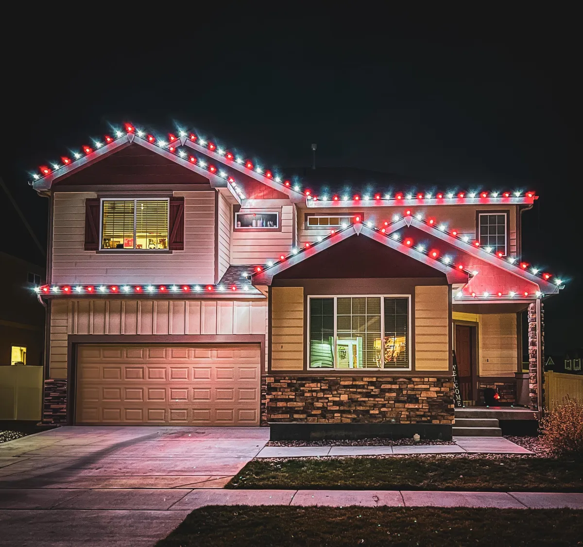 Two-story Timnath home outlined with cool white and red C9 LED roofline Christmas lights