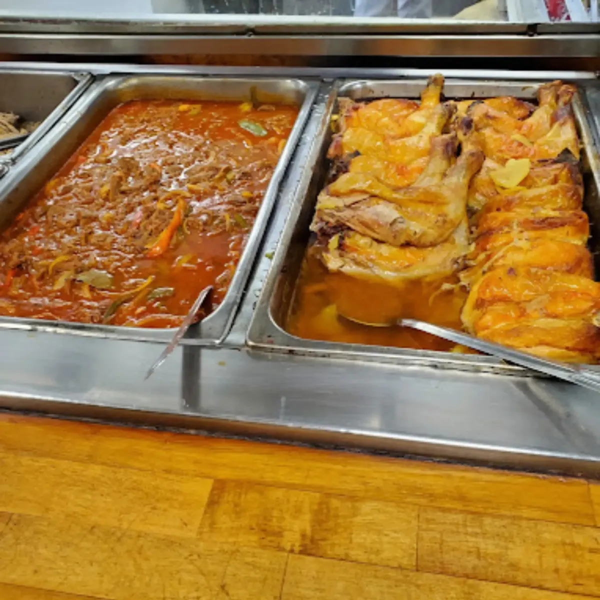 Close-up of authentic Latin American food at La Cocina, including crispy pork, saucy stewed meats, and golden-roasted chicken in rich flavorful sauces.