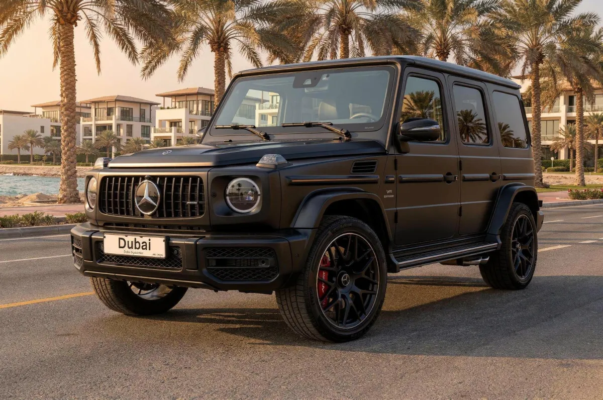 Matte black Mercedes AMG G63 parked on a Dubai roadside with palm trees and luxury villas behind