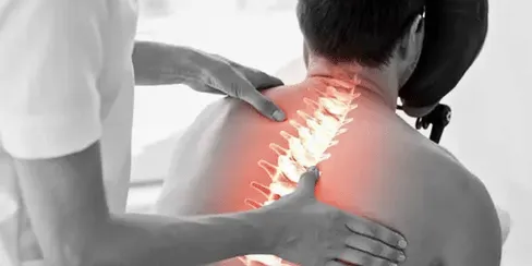 Patient receiving chiropractic care and massage therapy in Lawrenceville GA for back pain relief with a glowing spine visual overlay.