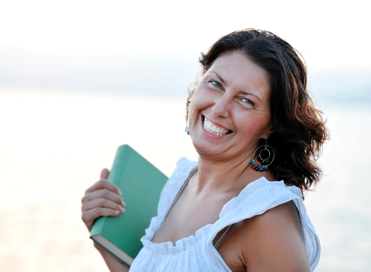 Woman smiling holding self-published book