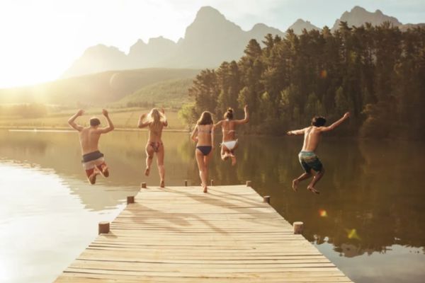Friends enjoying summer travel and outdoor vacation by a mountain lake