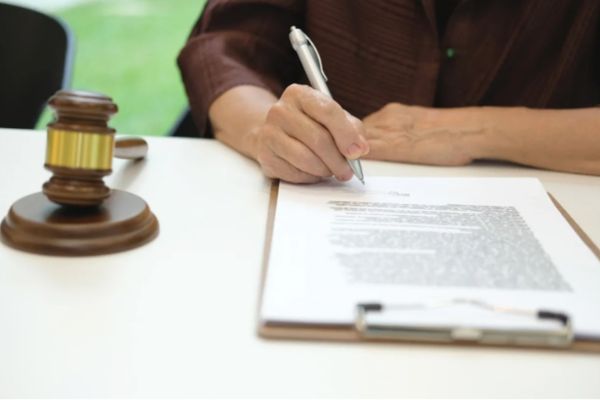 Person signing a notarized power of attorney document beside legal gavel for estate planning
