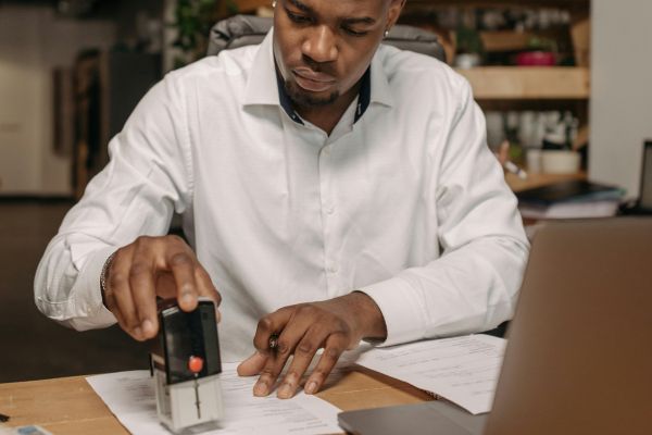 Professional mobile notary stamping legal documents at a desk in Miami with laptop and paperwork for real estate and business notarization services