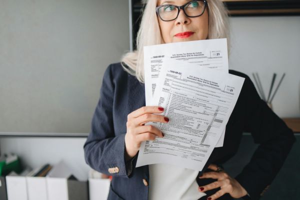 Woman reviewing tax forms and financial documents during tax season preparation for notarized IRS and legal paperwork