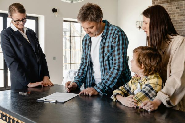 Family signing real estate closing documents with a notary during a home purchase transaction, highlighting mobile and online notary services for buyers and sellers in Miami, Florida.