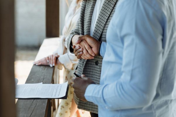 Real estate clients shaking hands after signing closing documents with a notary during a home purchase transaction in Florida