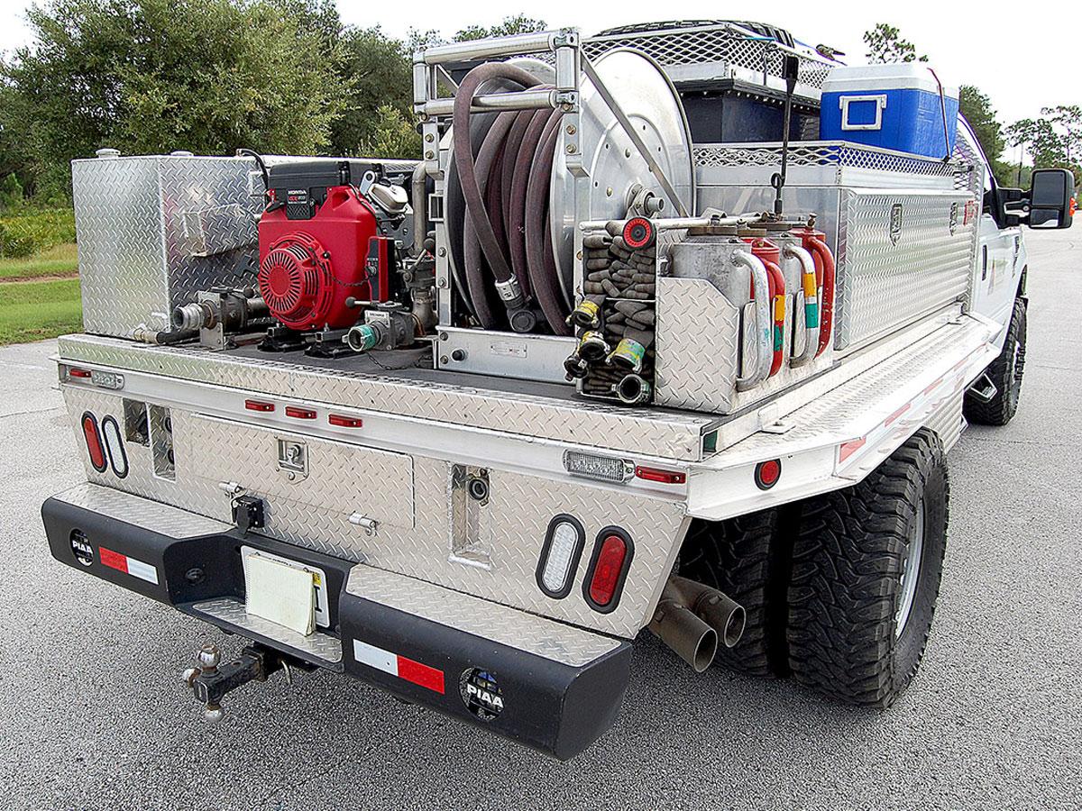 Wildland engine slip-on module on a utility truck bed showing hose ports and control panel.