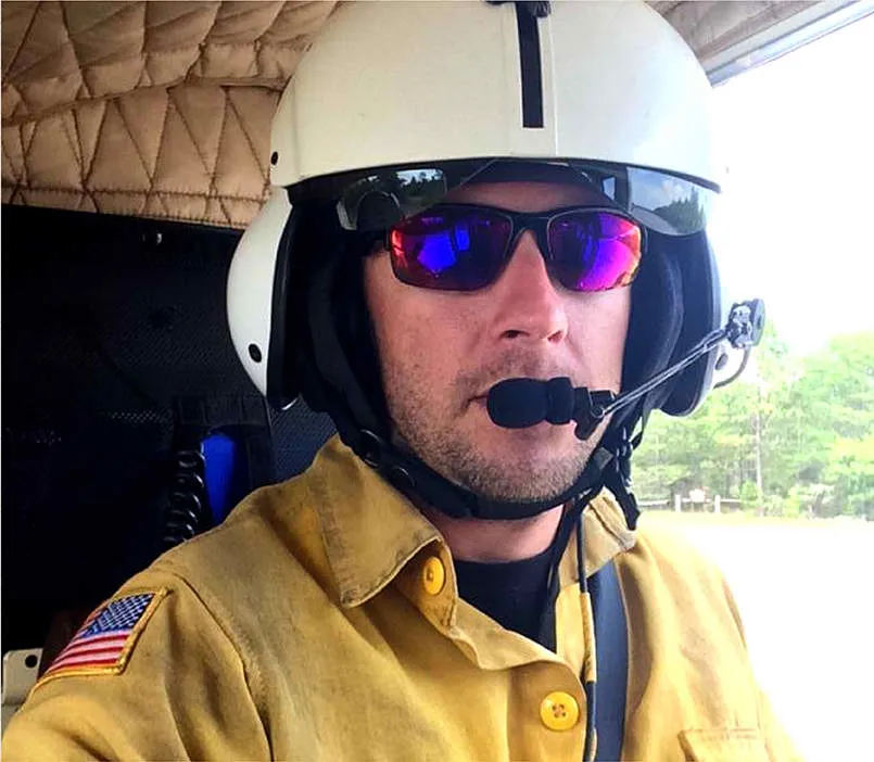 Southern Rough President Neil Clineman wearing wildland firefighter Nomex shirt and flight helmet in helicopter cockpit