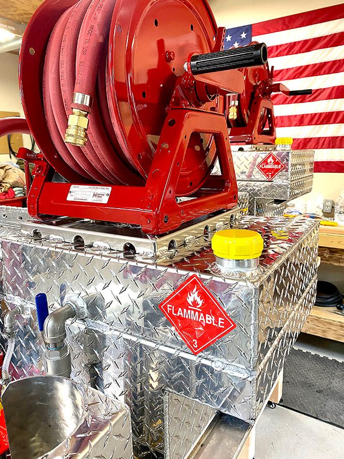 Southern Rough custom drip torch fuel cell with diamond plate aluminum construction, vented billet cap with o-ring, and red forestry hose reel mounted above