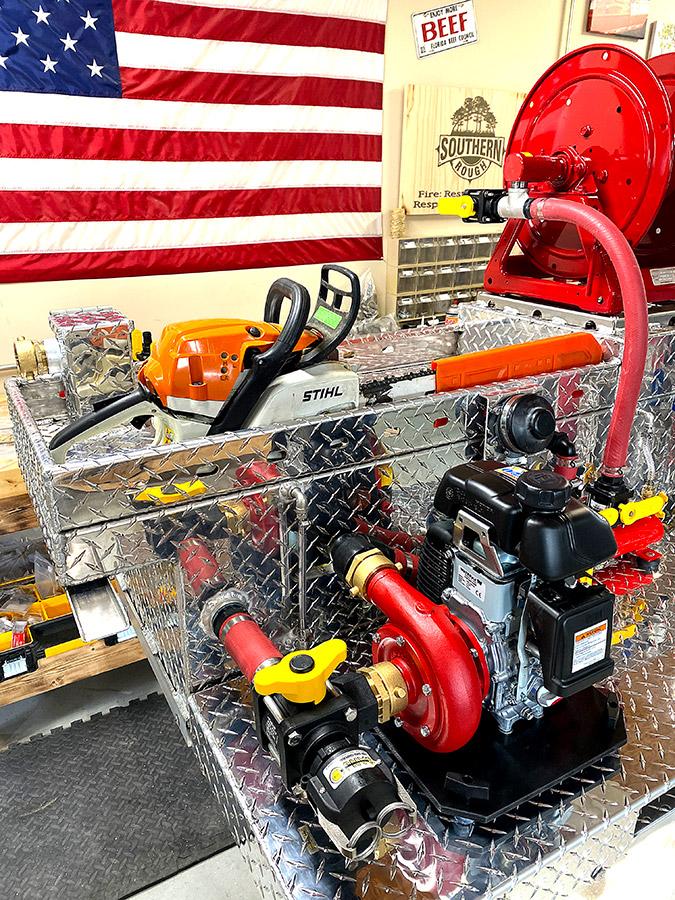 Southern Rough custom UTV fire skid featuring top tank storage rail system with Stihl chainsaw, forestry hose reel, and Waterax pump in fabrication shop