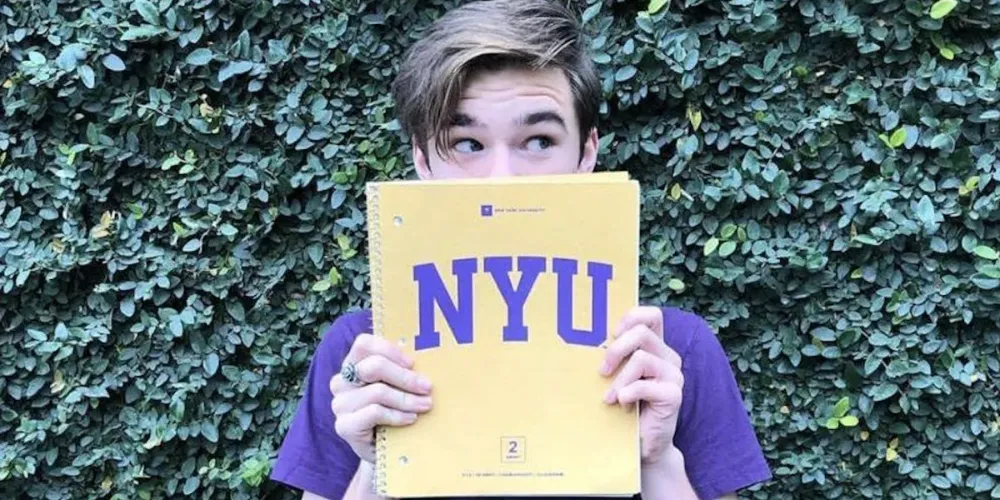 Young Man holding NYU Notebook over his face