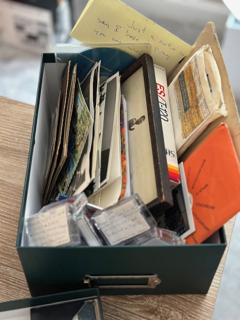 Magic Lantern Memories print photo organizing with a box of family photographs, albums, slides, and keepsakes awaiting organization and preservation.