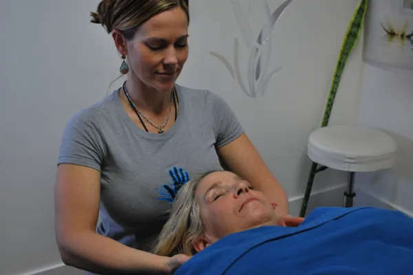 Therapist gently supporting a client’s head during a relaxing bodywork session at Alleviating Hands clinic