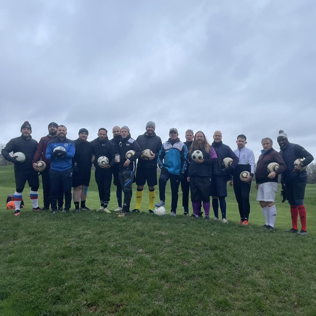 A large group of friends cheering and having fun while playing footgolf on a sunny fairway