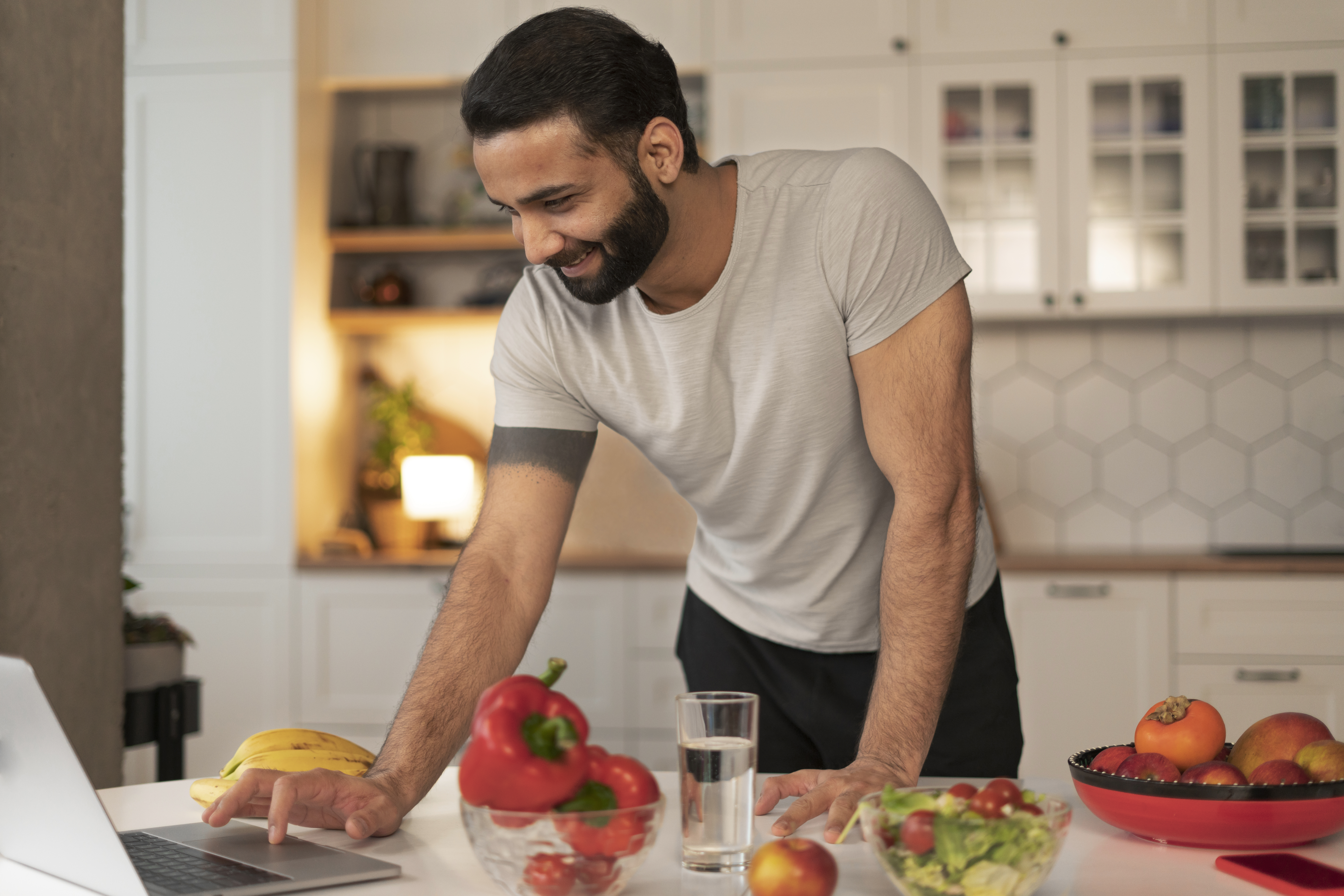 Smiling man jogging outdoors wearing a gray athletic shirt and headphones, promoting health and wellness through fitness.