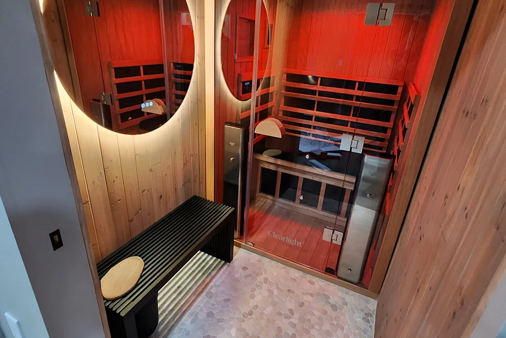 Infrared sauna interior with warm red lighting, wooden benches, and a relaxing atmosphere, promoting wellness and detoxification at Zel Vitality.