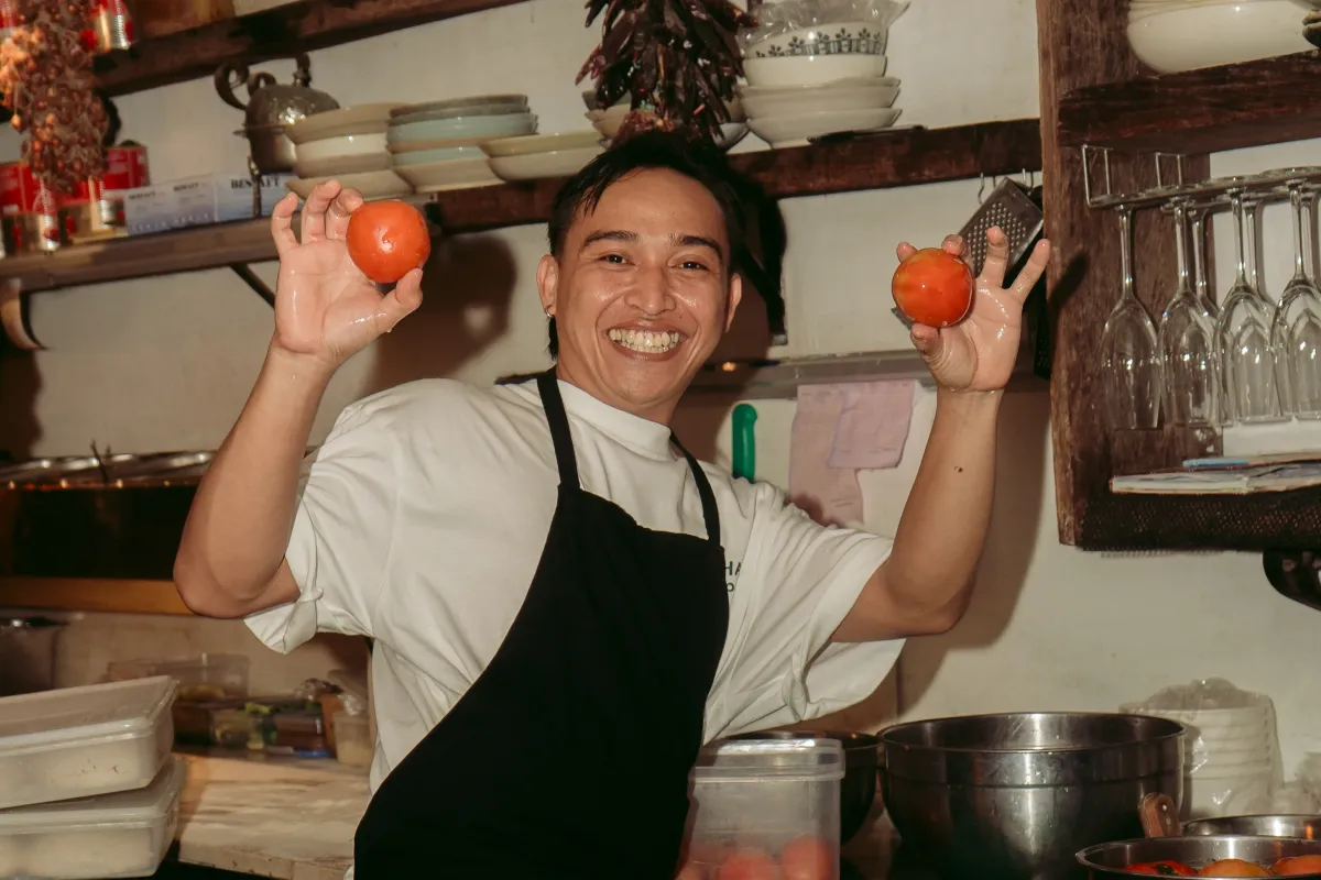 A chief holding a tomatoes.