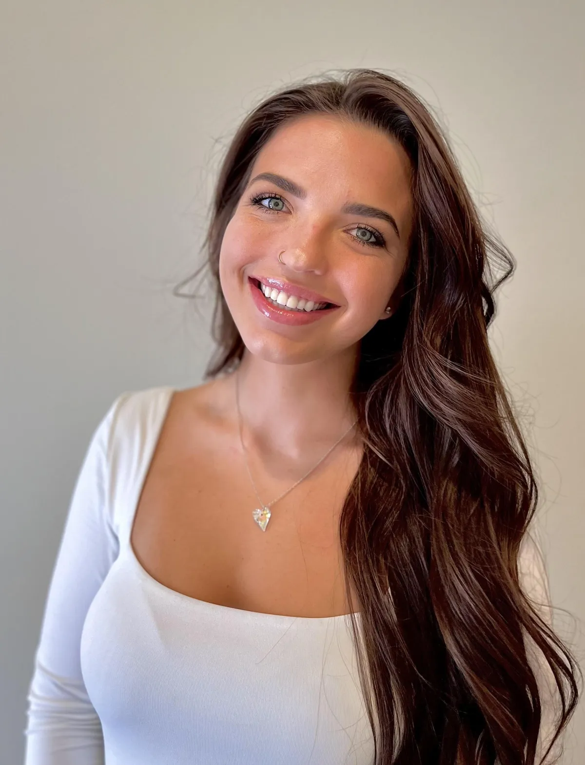 Kindred Benesh Wearing a white top and her hair down smiling into the camera