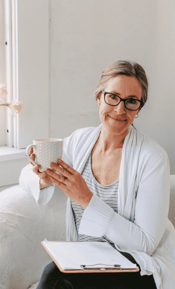 Paula Rice sitting with a cup of coffee and a clip board planning a perfect cut flower garden and coaching people on how to start growing and selling cut flowers.