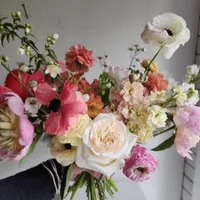 A bundle of cut flowers arranged in my hand in shades of pinks to showcase all the variety you can grow in your cut flower garden and sell as a bridal bouquet.