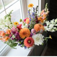 A beautiful orange colorful cut flower arrangement with dahlias to showcase a garden-florist arrangement.