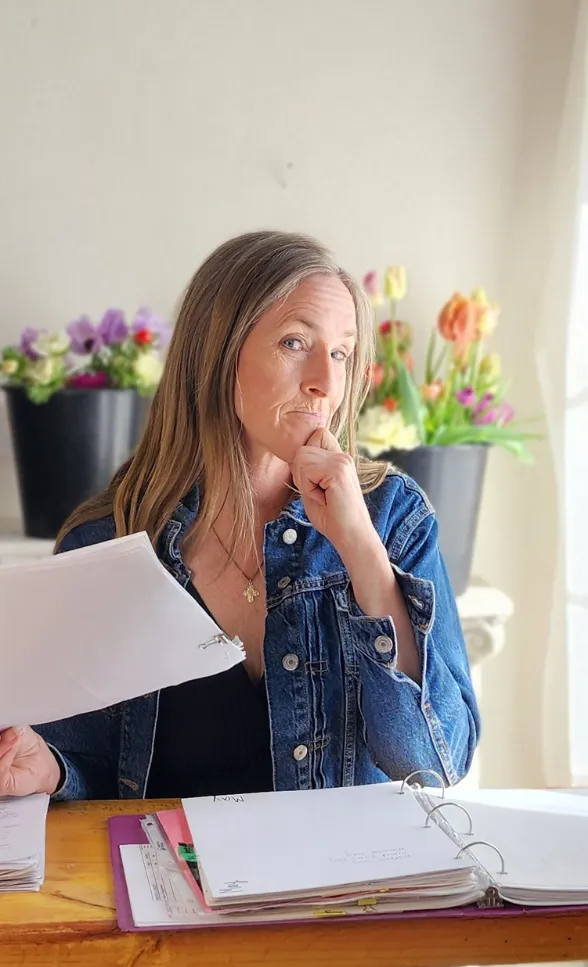 Paula Rice sitting with a cup of coffee and a clip board planning a perfect cut flower garden and coaching people on how to start growing and selling cut flowers.