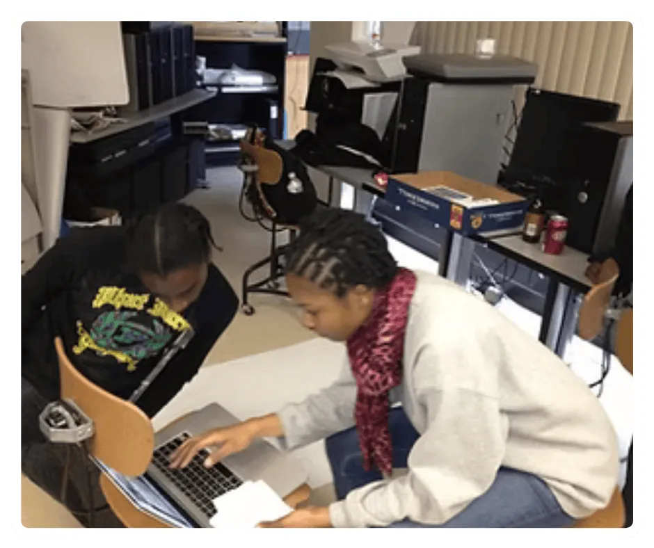 Students collaborating on video editing and media production using a laptop during EVT training program