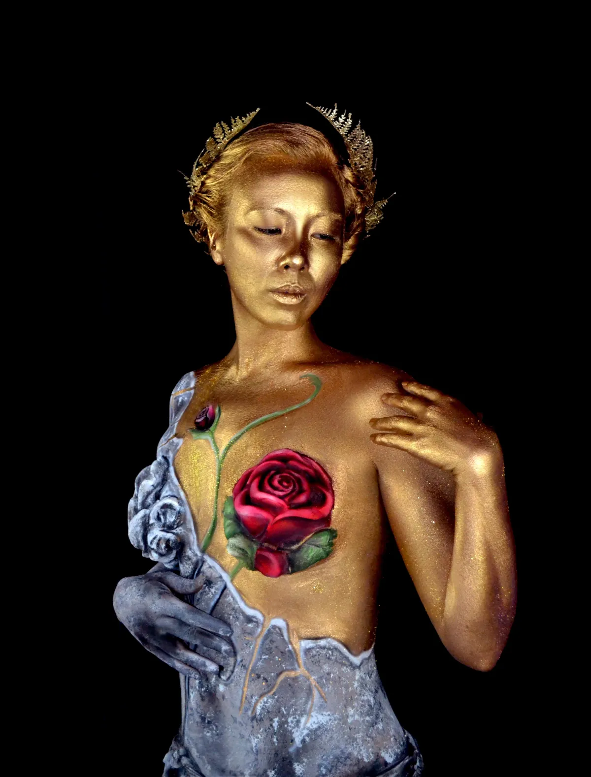 body painted muse, woman painted as a statue with a rose over her breast gold woman