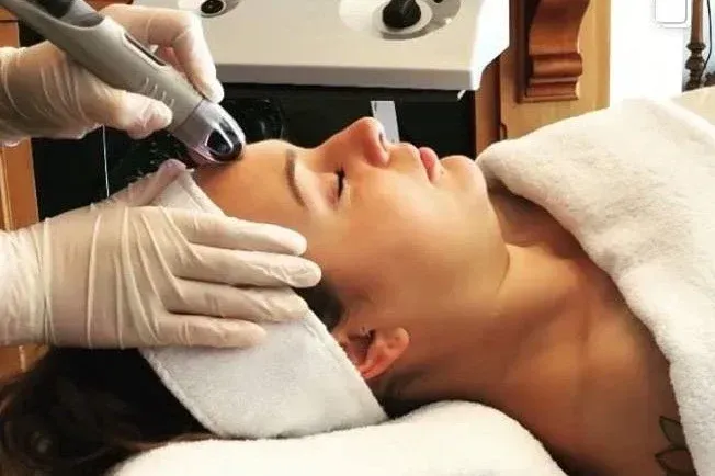Skin therapy image: therapist applying a targeted facial treatment, close-up on skin and tool, warm clinical tones.