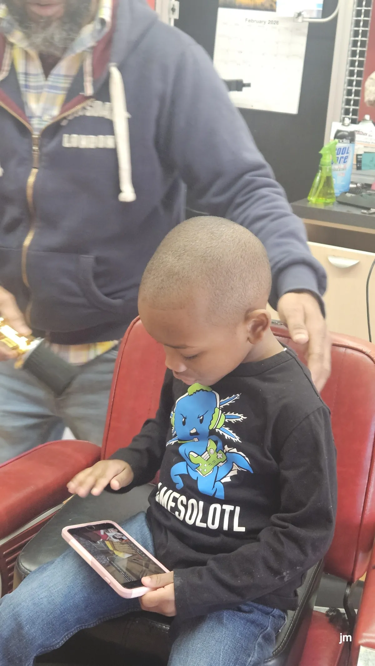 kid playn on phone after haircut