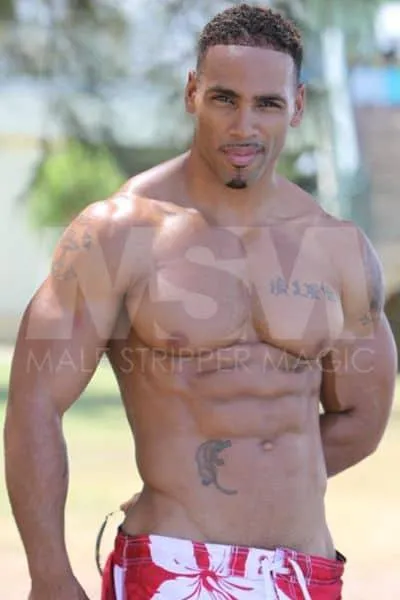 Genuine, a black male stripper, posing outdoors in swimwear