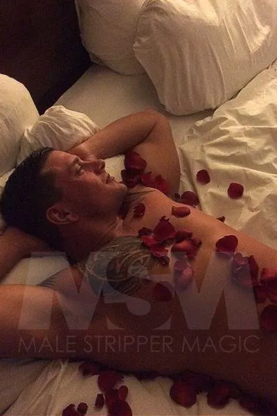 Male stripper Dean in a romantic bedroom setting with rose petals