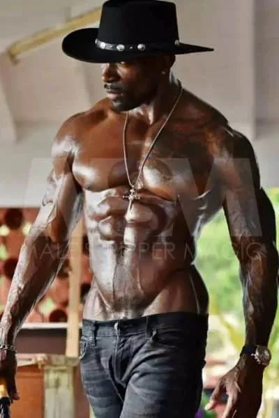 Muscular black male stripper Swagg in cowboy attire, shirtless with a silver chain
