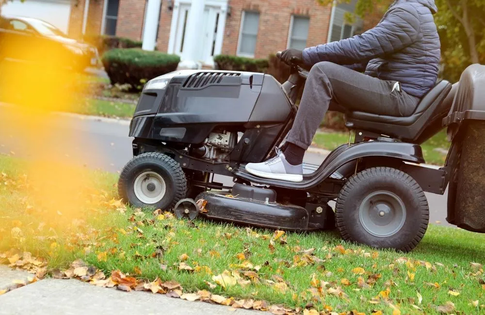 person on law mower removing grass and leaves